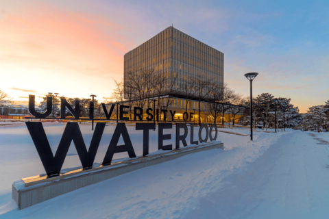 A sign which says "University of Waterloo" with a sunset behind it, and snow surrounding it.