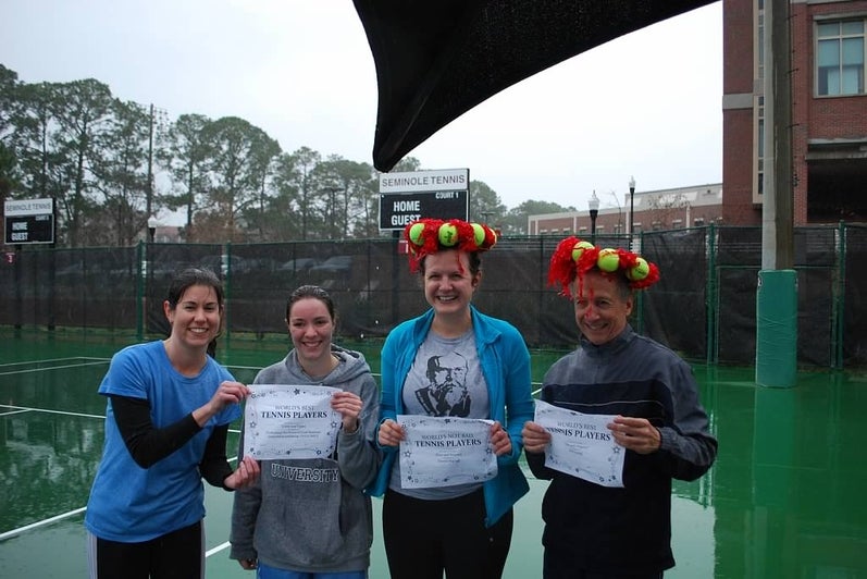 A photo of lab members with yellow and red tennis ball crowns smiling and holding certificates.
