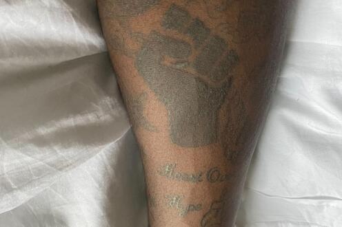 Black Lives Matter fist tattoo in black ink on black skin on a forearm.