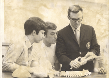 Professor and two students examining spine model.