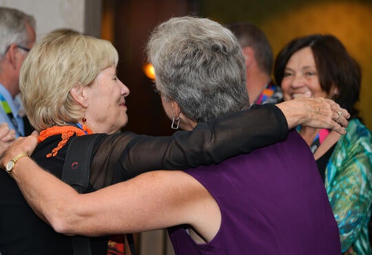 Class reunion guests greeting each other with hug.