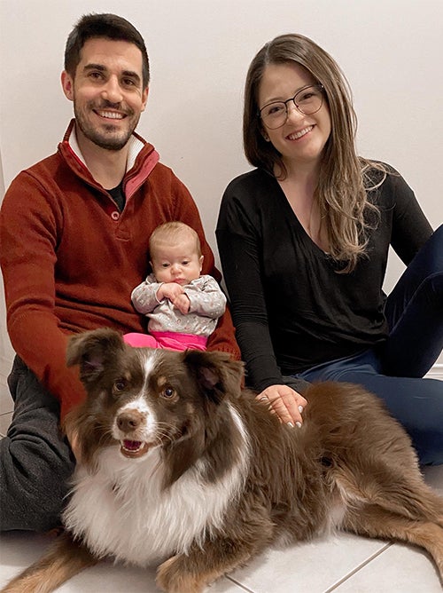 Kurtis holding baby daughter with Janna and family dog.