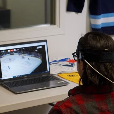 Subject wearing spectroscopy headband watches hockey game on a laptop.