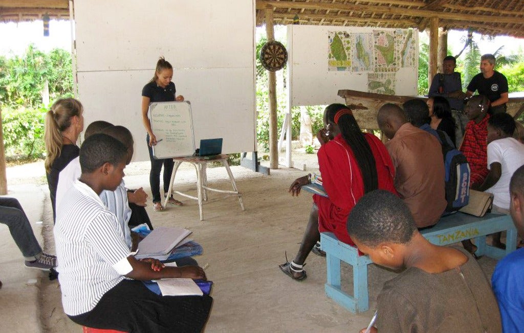 Educator demonstrates at front of open air classroom.