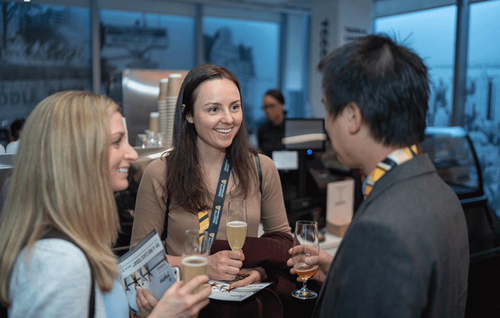 Three alumni smiling and chatting at a reception.
