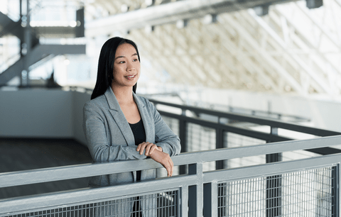 Hoang Tang stands at railing wearing suit, smiling.