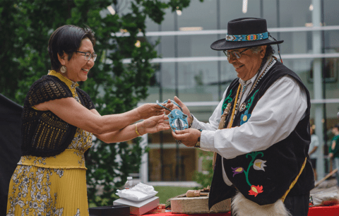 Lili Liu and Myeengun Henry present beaded gift at recommitment ceremony.