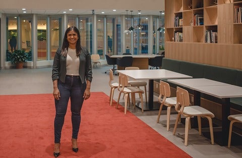 Shelly-Ann Rampersad stands smiling in a library lounge.