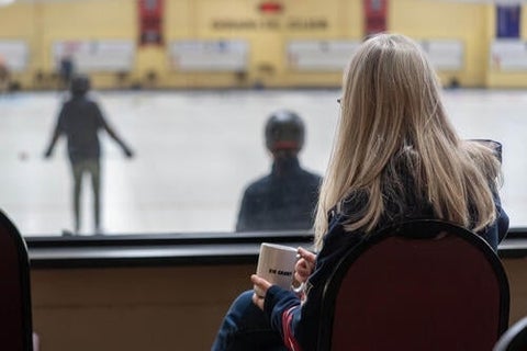 Heather Mair seated at rink looking out at the ice (over the shoulder).