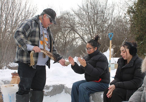 Indigenous Elder with students at firepit outdoors.
