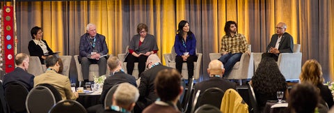 National and community leaders panel with audience in foreground.