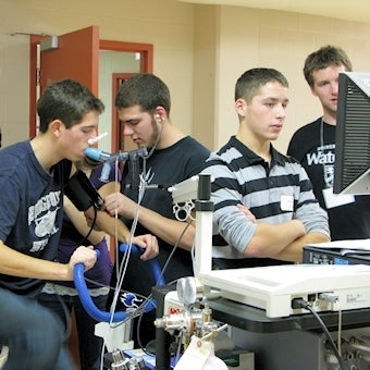 Group of high school students using cycle ergometer in a Kinesiology lab.