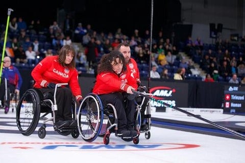 Team Canada's wheelchair curling team in action on the ice.