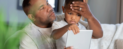 Father checks forehead temperature of young son.