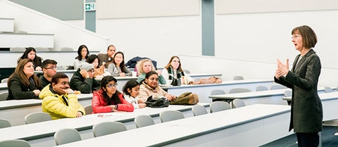 Professor in health social determinants class talks to group of students.