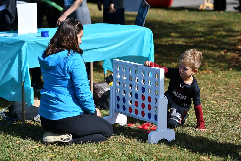 Child playing Connect4 with Fun Run volunteer