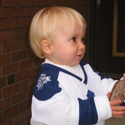 A little boy wearing a Toronto Maple Leafs hockey unifrom