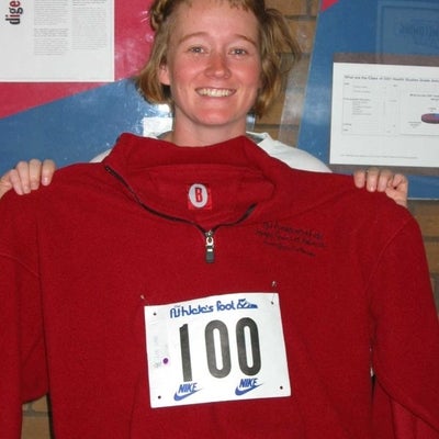 A female participant holding a red sweater with number 100 sticker in the middle