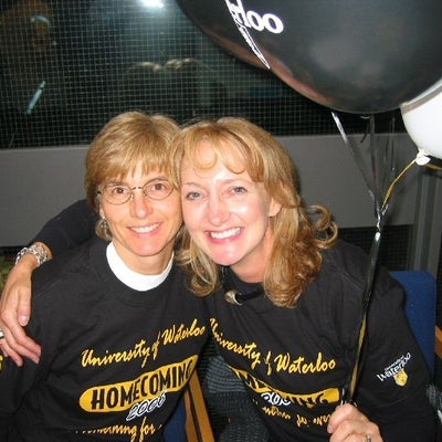 Two females in University of Waterloo t-shirts putting arms around each other's shoulders