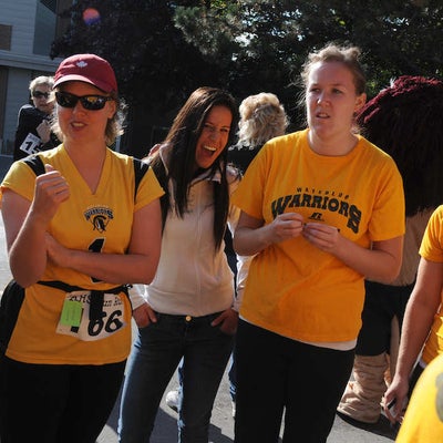 Three females focused among other people while a girl in the middle shows excitement through her facial expression
