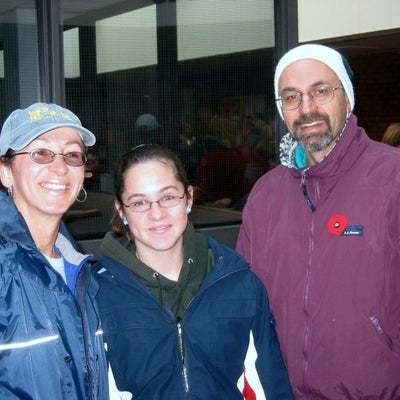 Two females and a man who has poppy on his jacket smiling towards camera