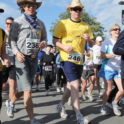 View of people jogging while focusing two male runners wearing cowboy hats