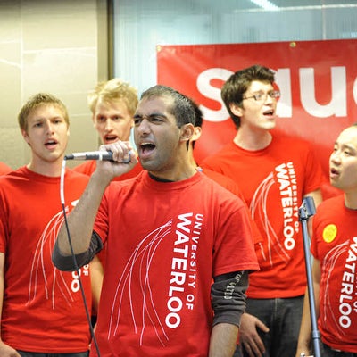 A male singing with a microphone among other people