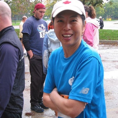A female runner with a white hat and blue t-shirt looking towards the camera