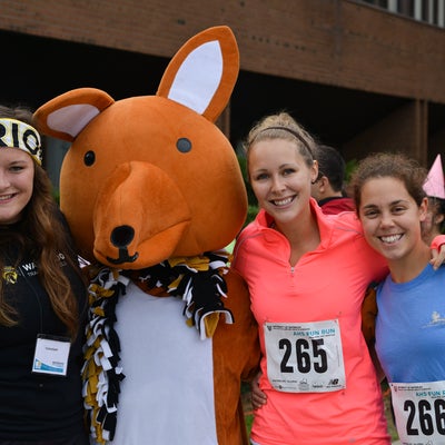 Three students posing for a photo with a kangaroo mascot.