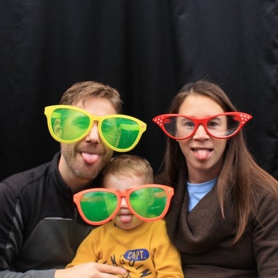 A man and woman wearing funny large glasses with a baby.