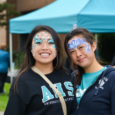 Two students smiling for a photo with face paintings.