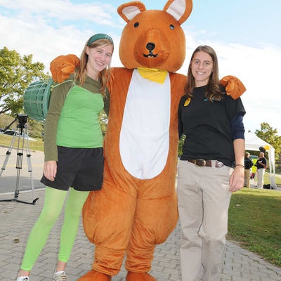 A bear mascot standing with two females on right and left