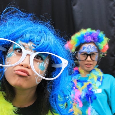 Two students with face paintings wearing funny glasses, wigs and scarves.