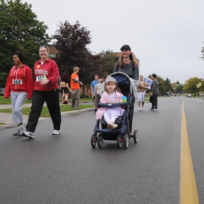 People in the race while focusing on a woman with her baby in a baby stroller