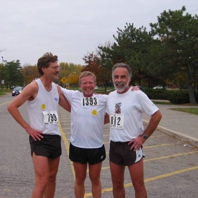 Three male runners putting arms around each other's shoulders