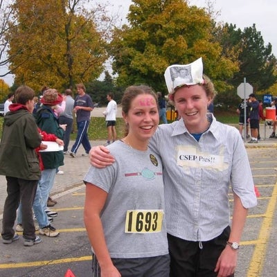 Two female runners with grey shirts with pictures and letter stuck on top