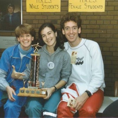 Female holding and pointing at trophee, sitting with her friends.