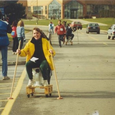 A girl riding on a toilet cart.