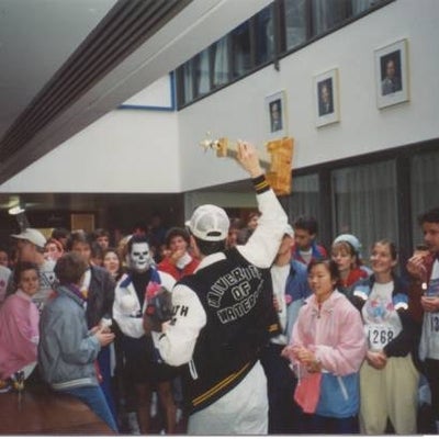 A winneer of the race holding a trophy after the race with other participants. 