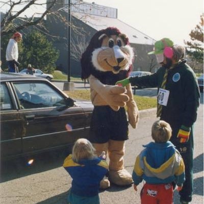 A lion mascot shaking hands with a man