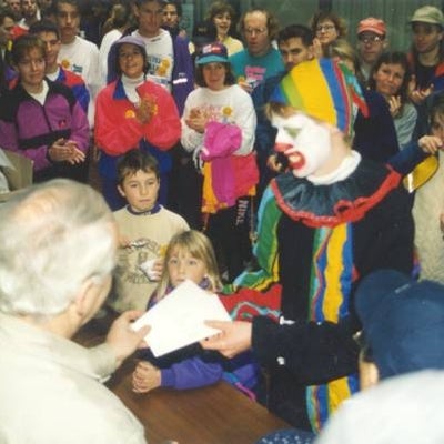 A man with a clown costume receiving a certificate during the after meeting.