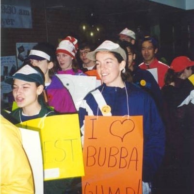 Two females with signs being focused saying "I LOVE BUBBA GUMP!" among people