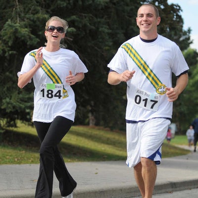 Two runners wearing matching white shirts with diagonal stripes