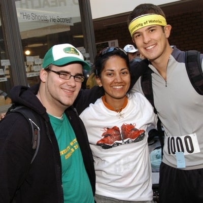 Two male runners and a female runner smiling towards a camera