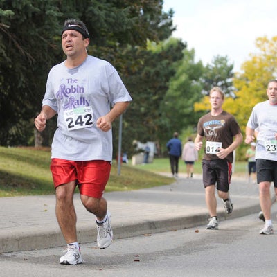 A man looking really tied running in front of other participants