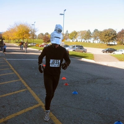 A man running in a track suit with alumini foil made roman helmet on his head