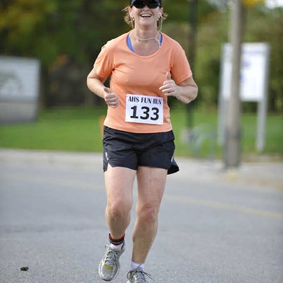 A female runner wearing a black cap and sunglasses running while listening music 