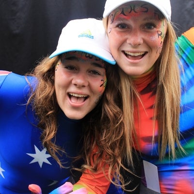 Two ladies wearing full body suits wearing hats and have their face painted.