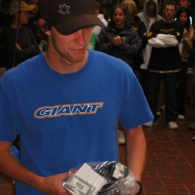 Man wearing a black hat and blue shirt holding a package in a plastic bag