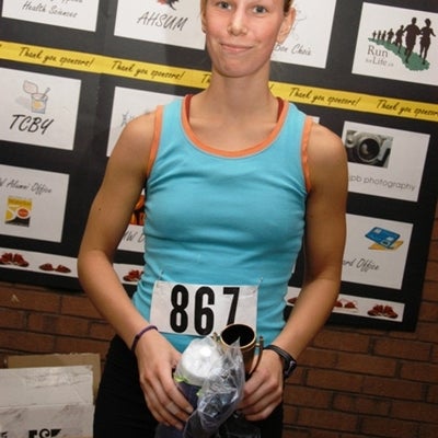 A female runner holding her trophee and a package in a plastic bag